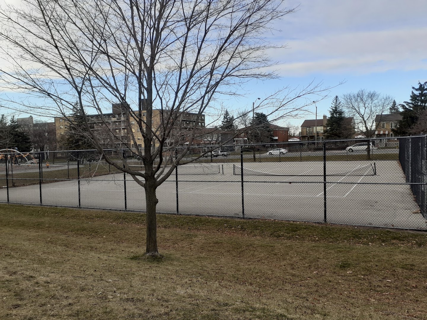 Empty fenced outdoor court with tennis net at Amesbury Park, Toronto