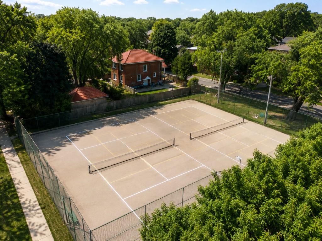 Two fenced outdoor tennis and pickleball courts at Birch Park with yellow lines and light poles